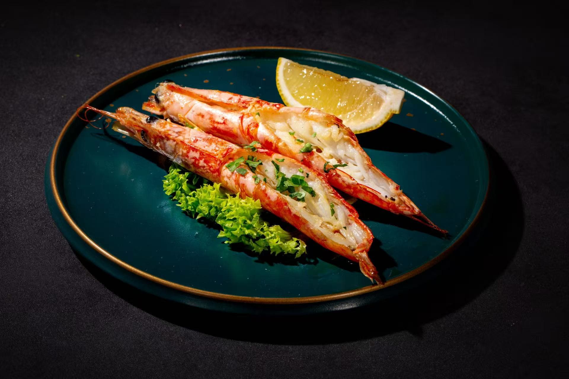 Grilled prawns with lemon on a deep green plate