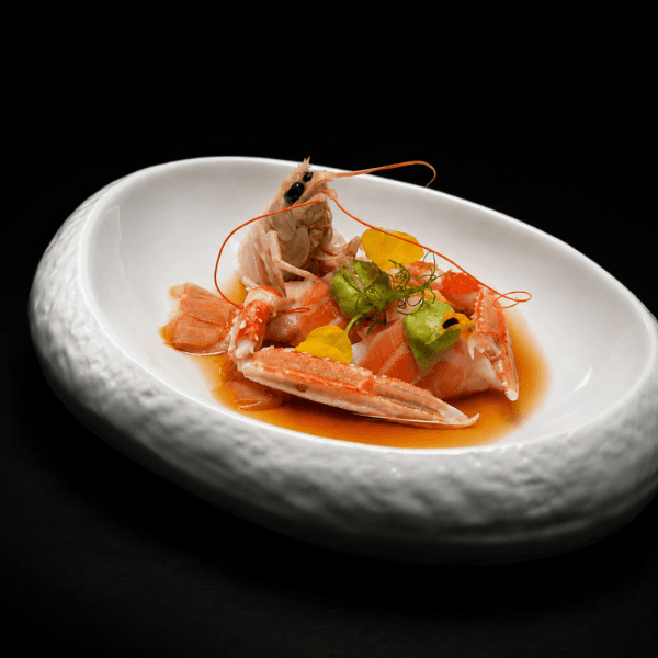 Langoustine crudo with salmon and sauce in a white bowl