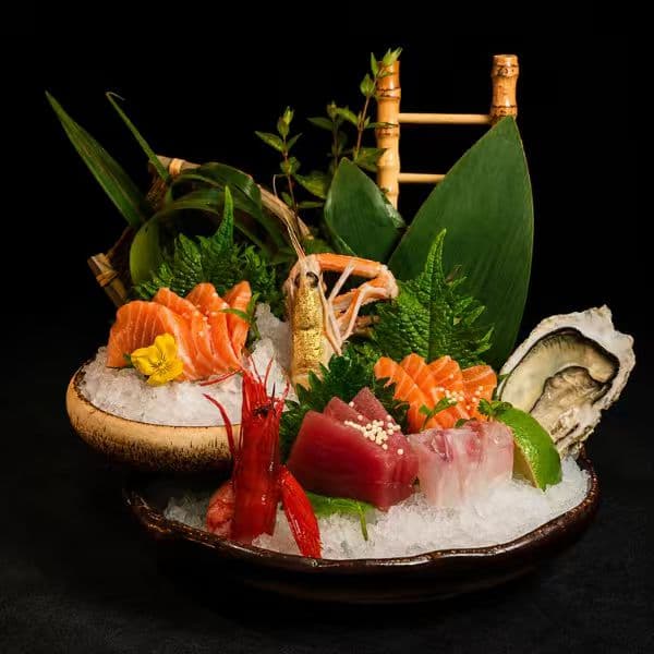 Premium sashimi selection arranged over ice with oyster and herbs